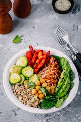 Vegetable bowl lunch with grilled chicken and quinoa, spinach, avocado, brussels sprouts, paprika and chickpea