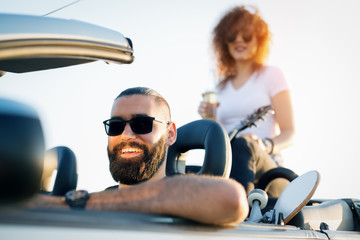 Couple On Road Trip Sit On Convertible Car