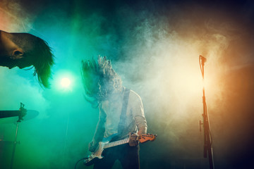 Rock band performs on stage. Guitarist, bass guitar and drums.