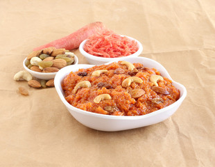 Carrot halwa or pudding, a traditional, popular and delicious Indian sweet dish, along with carrot gratings and almonds, raisins and cashew nuts.