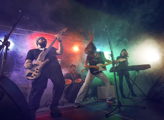 Naklejka premium Rock band performs on stage. Guitarist, bass guitar and drums.