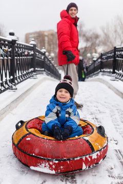 Photo of father of skating son on tubing in winter park
