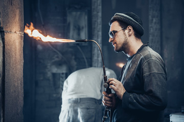 Closeup of a beautiful worker in a hat and with a Spanish beard, which adjusts the gas appliance to...