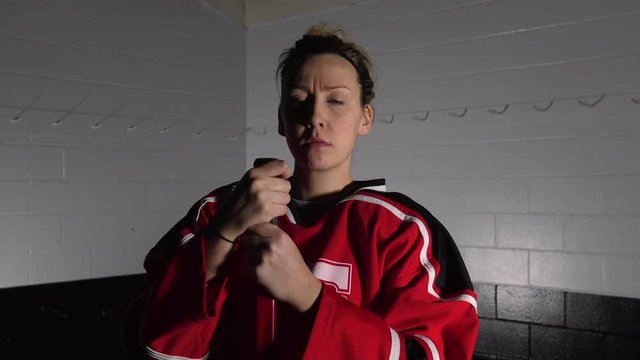woman hockey player posing with her stick serious facer dramatic lighting