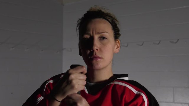 woman hockey player posing with her stick serious facer dramatic lighting close up