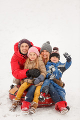 Picture of happy family with daughter and son sitting on tubing in winter