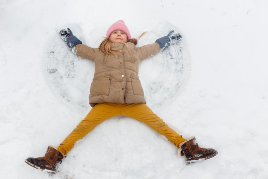 Image of girl lying on her back in snow at park