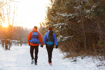 Romantic picture from back of man and woman with backpacks in winter