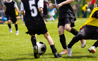 Fototapeta na wymiar Soccer Players Competing For The Ball. Primary School Football Game. Soccer Tackle. Youth Soccer Teams Tournament Match