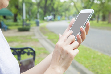 Woman hand holding mobile phone and touch screen  with clipping path at screen mobile in park.