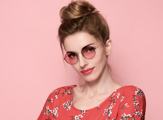 Beautiful Girl in Summer Floral dress Smiling. Fashion Young woman, Trendy Sunglasses. Studio Portrait Playful Model in Spring Summer Outfit. Pretty Lady on Pink