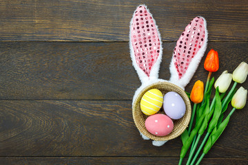 Top view shot of arrangement decoration Happy Easter holiday background concept.Flat lay colorful Easter egg with tulip flower and bunny ear on modern brown wooden at office desk.space for mock up