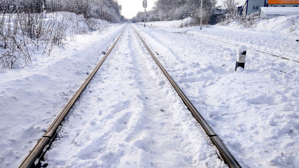 Fototapeta premium The path between the sleepers in with a bliss. Sleepers from the train, electric train in city in the winter. They are covered with snow from a storm. The road going into the distance.