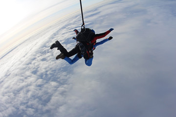 Fototapeta na wymiar Skydiving. Tandem is flying above white clouds.
