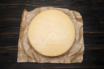Whole round Head of parmesan or parmigiano hard cheese on wooden background