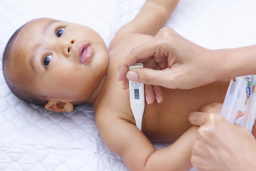 Mother Measures The Temperature Of Her Baby Using Digital Thermometer 