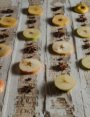 apples cut in circles with coffee beans and star anise on a rough wooden surface, toned creative background