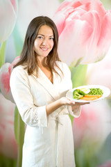 A young woman is holding a plate of boiled vegetables. Propaganda of proper nutrition.