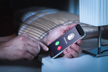 Unknown number calling in the middle of the night. Phone call from stranger. Person holding mobile...
