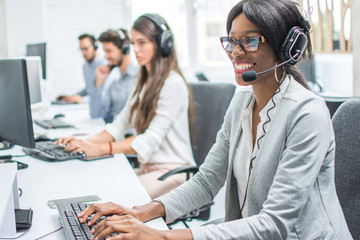 Smiling young woman with headset working in call center.