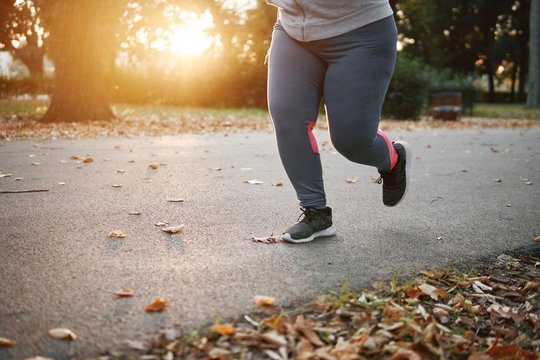 Curvaceous young female runner running in park, waist down