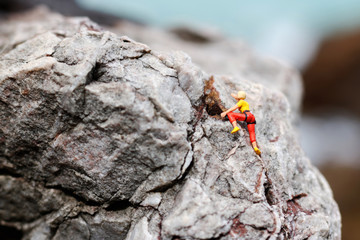 Miniature people: Climber looking up while climbing challenging route on cliff, Concept of the path to purpose and success.