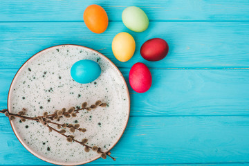 Easter eggs in plate on blue wooden table background