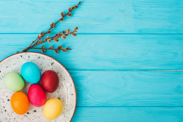 Easter eggs in plate on blue wooden table background