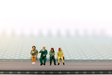 Miniature people: business team sitting on book with coffee break. Concept of education and business.