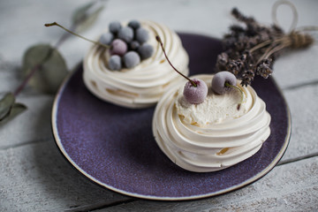 Pavlova cakes with cream and freezed berries. Pastel colors and small bouquet of lavender. Background of white boards. - 191995231