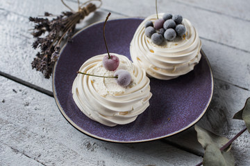 Pavlova cakes with cream and freezed berries. Pastel colors and small bouquet of lavender. Background of white boards. - 191995255