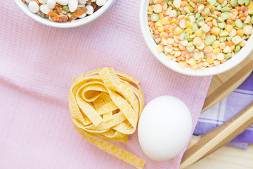 Set of raw ingredients for Italian pasta on a white background. Flour, eggs, olive oil. Set of healthy food products. Closeup and top view