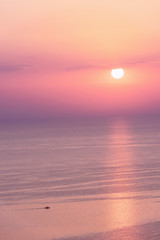 Nice pink sunset seascape in pastel shades, peace and calm outdoor travel background with copy space, vertical image