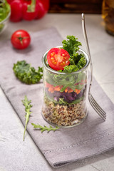 Quinoa salad in glass jar with arugula and kale, healthy snack, diet and vegan food concept