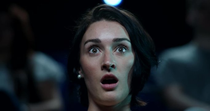 A terrified young woman reacts to a horror film