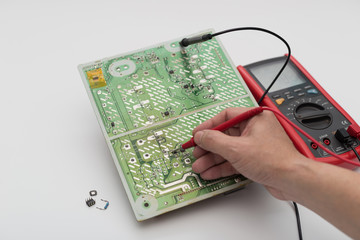 Engineer repairing electronic circuit board with multimeter.