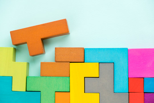 Different colorful shapes wooden blocks on blue background, flat lay. Geometric shapes in different colors, top view. Concept of creative, logical thinking or problem solving. Copy space.