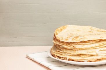 Pancakes on a saucer on a kitchen towel. Many pancakes are stacked. Thin pancakes with crispy crust. Maslenitsa. Pancakes for breakfast and carnival.