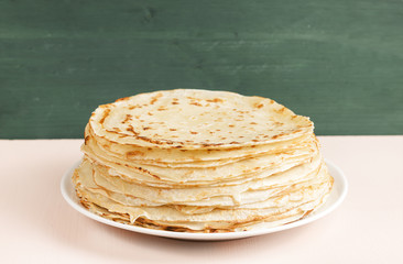 Pancakes on a saucer on a kitchen towel. Many pancakes are stacked. Thin pancakes with crispy crust. Maslenitsa. Pancakes for breakfast and carnival. Food background