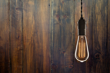 Vintage bulb on wooden background - idea, innovation and leadership concept. Space for text