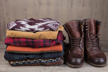 Pile of knitted winter sweaters on wooden background