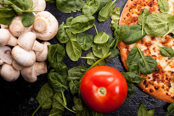 Top view of mushrooms, spinach leaves, tomatoes and pizza
