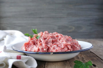 Fresh raw ground meat in a plate on a wooden table