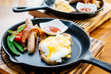 Egg benedict with sausage bacon and tomato sauce
