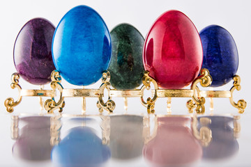 Five marble textured stone easter eggs on gold stands for eastern holiday in purple, blue, green, violet and red. - 192002429