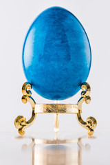 One marble textured stone epensive blue and fashionable easter egg on a gold stand for easter holidays. - 192002455
