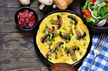 Frittata with mushrooms and cheese for breakfast with salad on a wooden background.