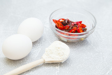 Set of raw ingredients for Italian cooking on stone table background. Eggs, sun dried tomatos, flour. Set of healthy food products. Closeup