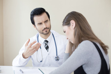 Attractive Doctor working at hospital. Doctor try to treat woman for any problem. He holding her hand.