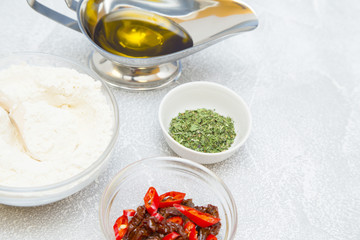 Set of raw ingredients for Italian cooking on stone table background. Eggs, sun dried tomatos, flour, olive oil and pasta. Set of healthy food products. Closeup